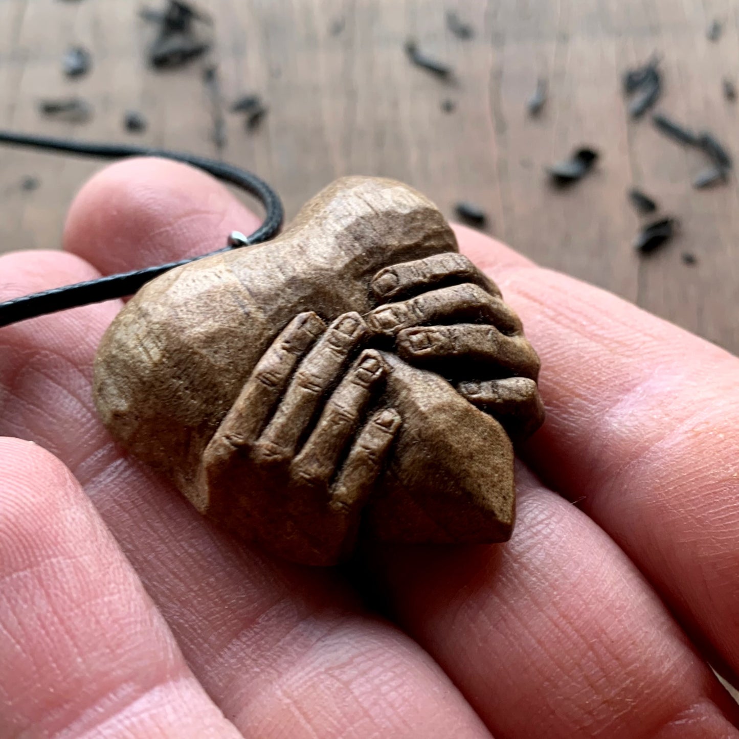 Hands squeezing a Heart Pendant