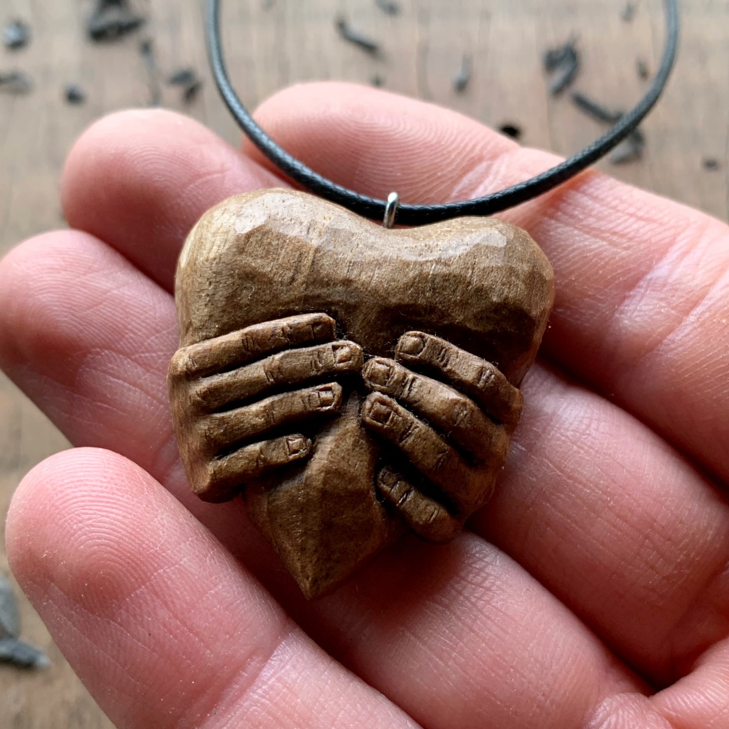 Hands squeezing a Heart Pendant