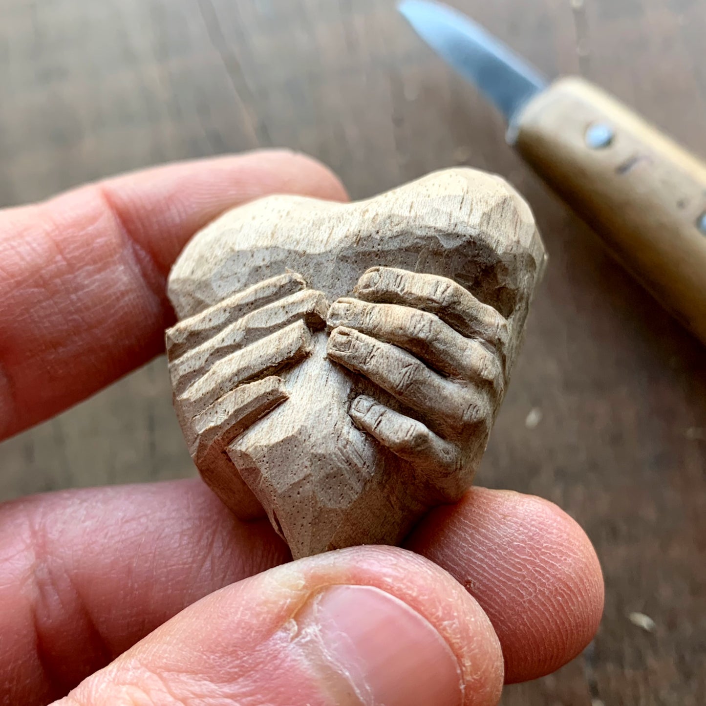 Hands squeezing a Heart Pendant