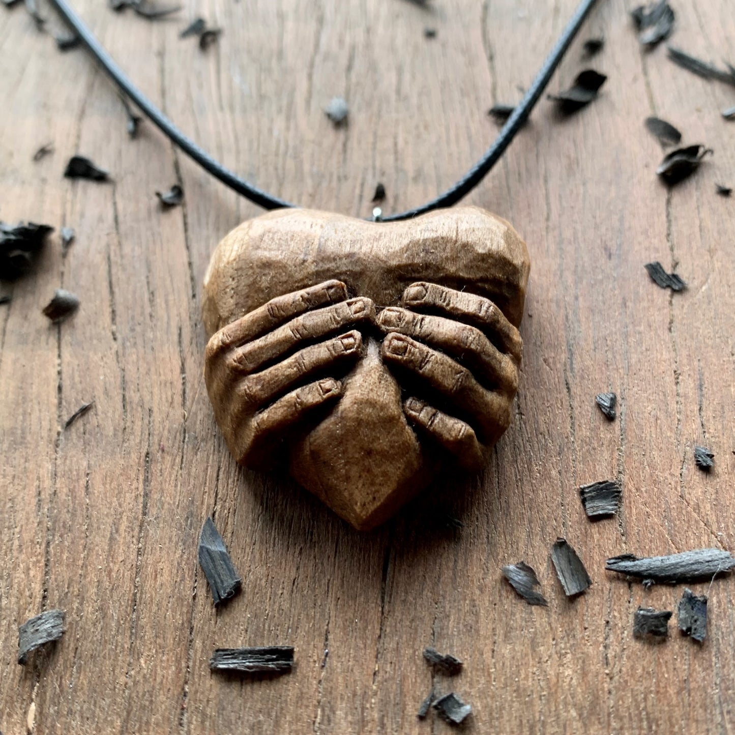 Hands squeezing a Heart Pendant