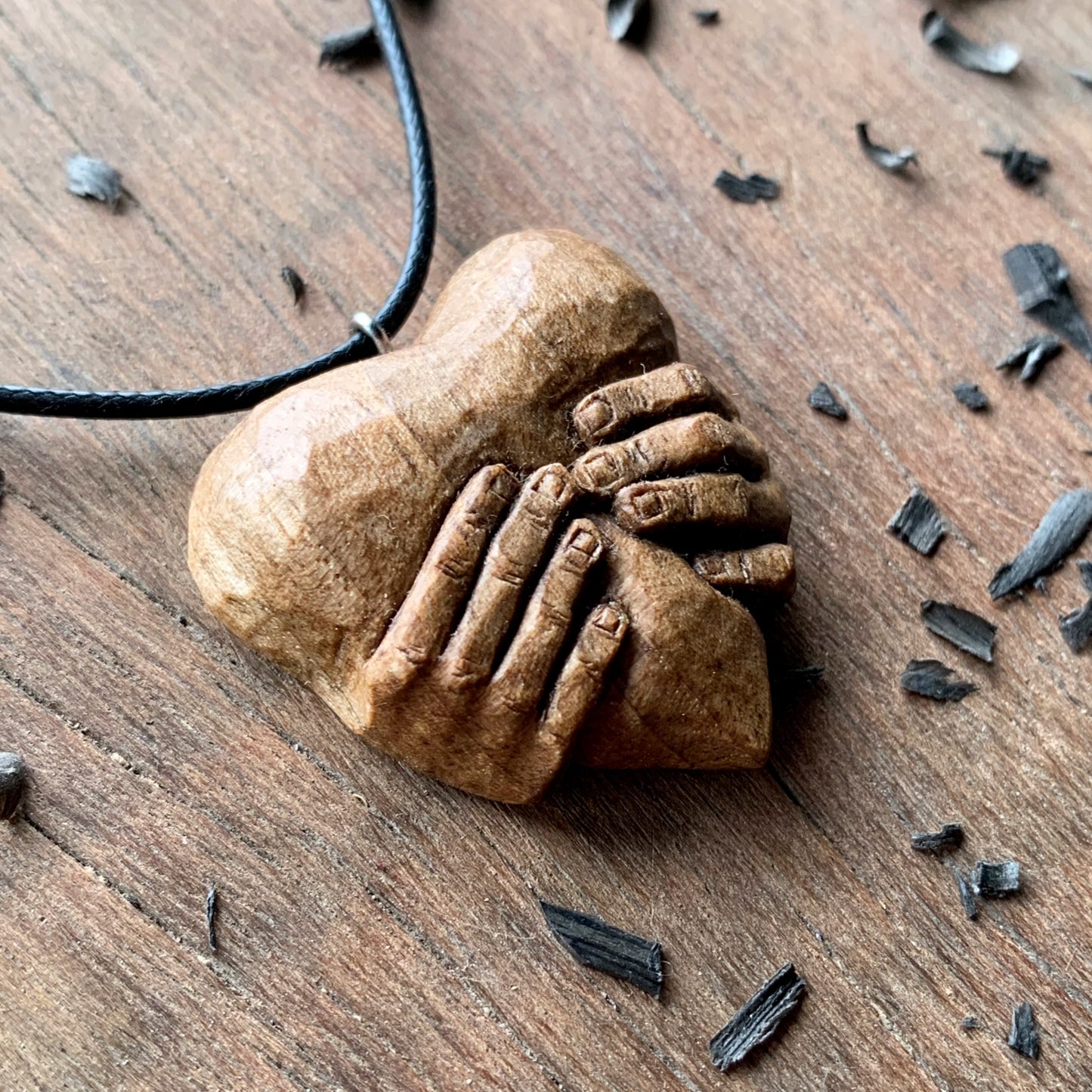 Hands squeezing a Heart Pendant