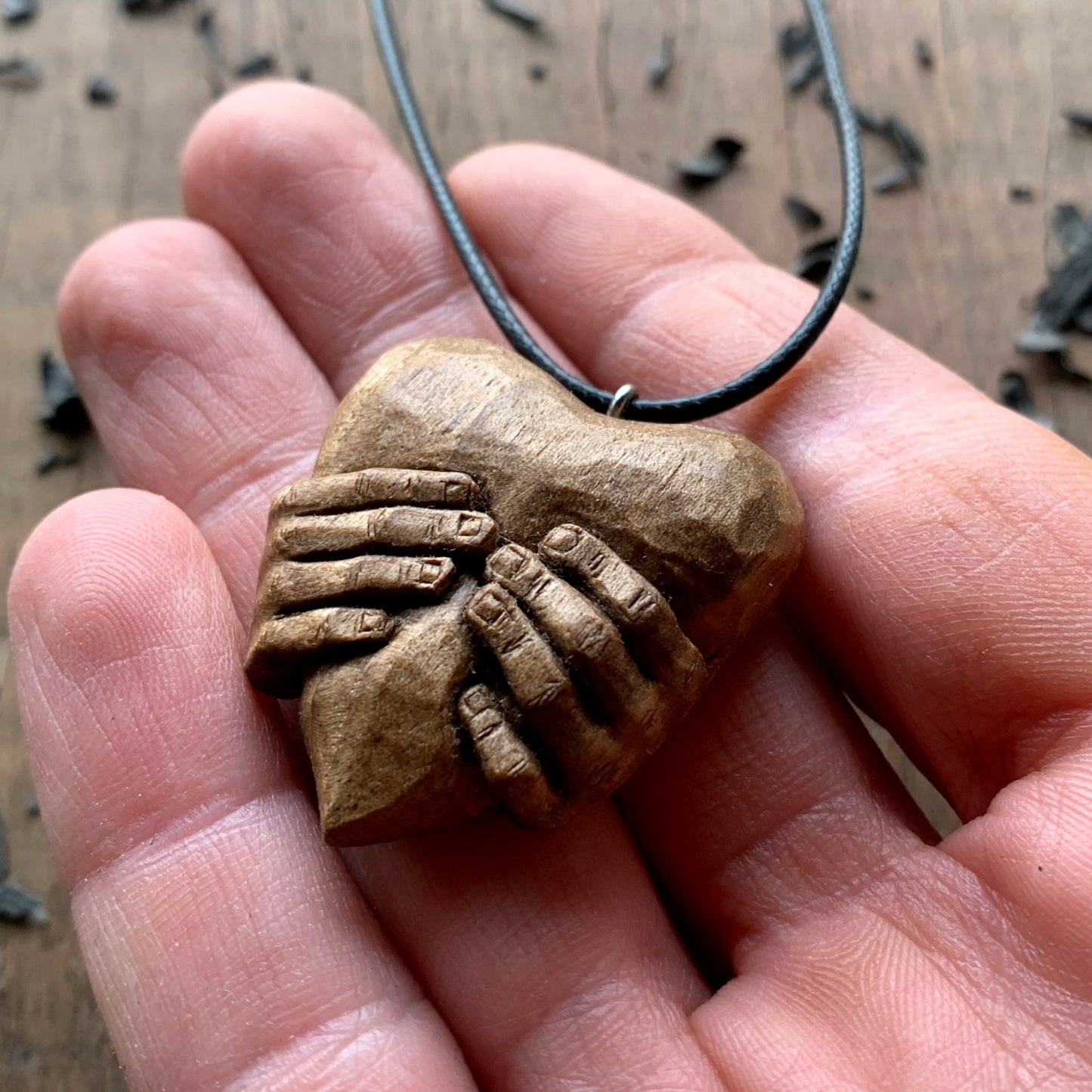 Hands squeezing a Heart Pendant