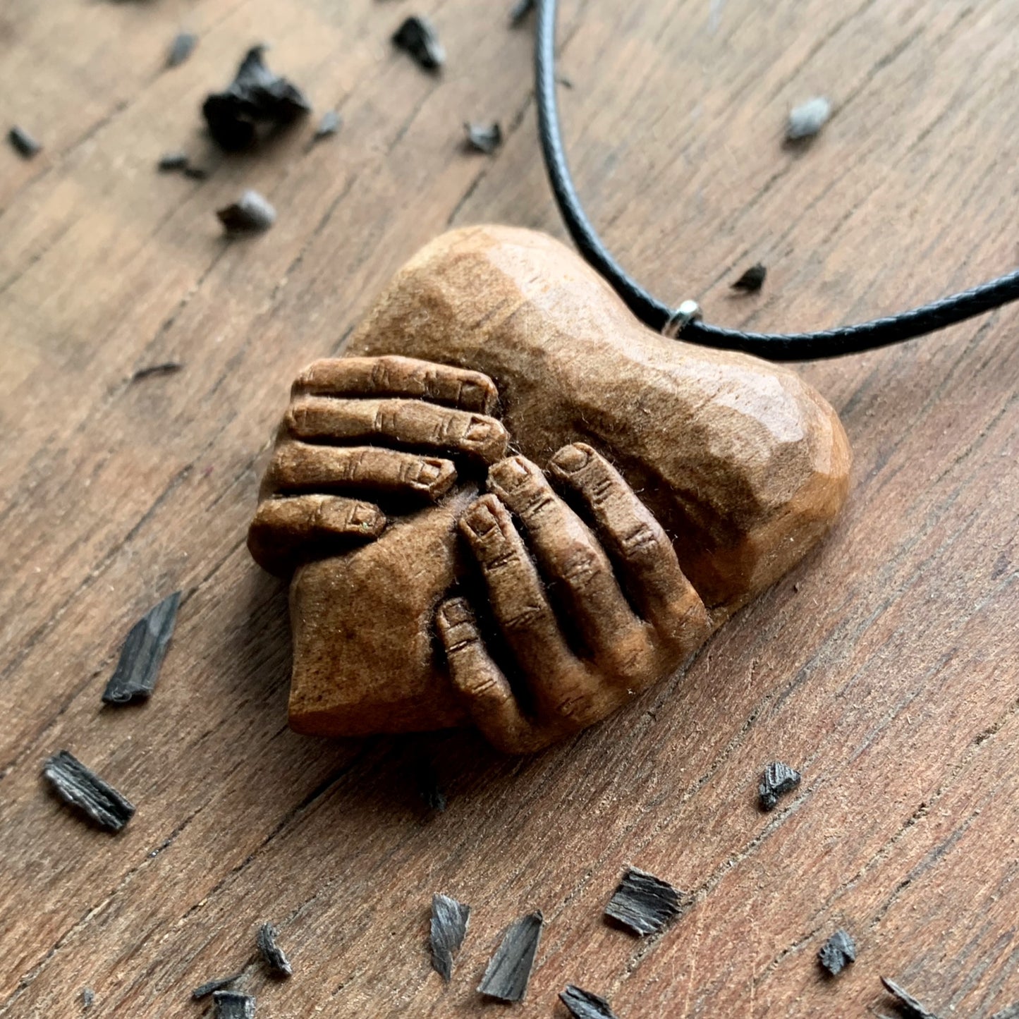 Hands squeezing a Heart Pendant