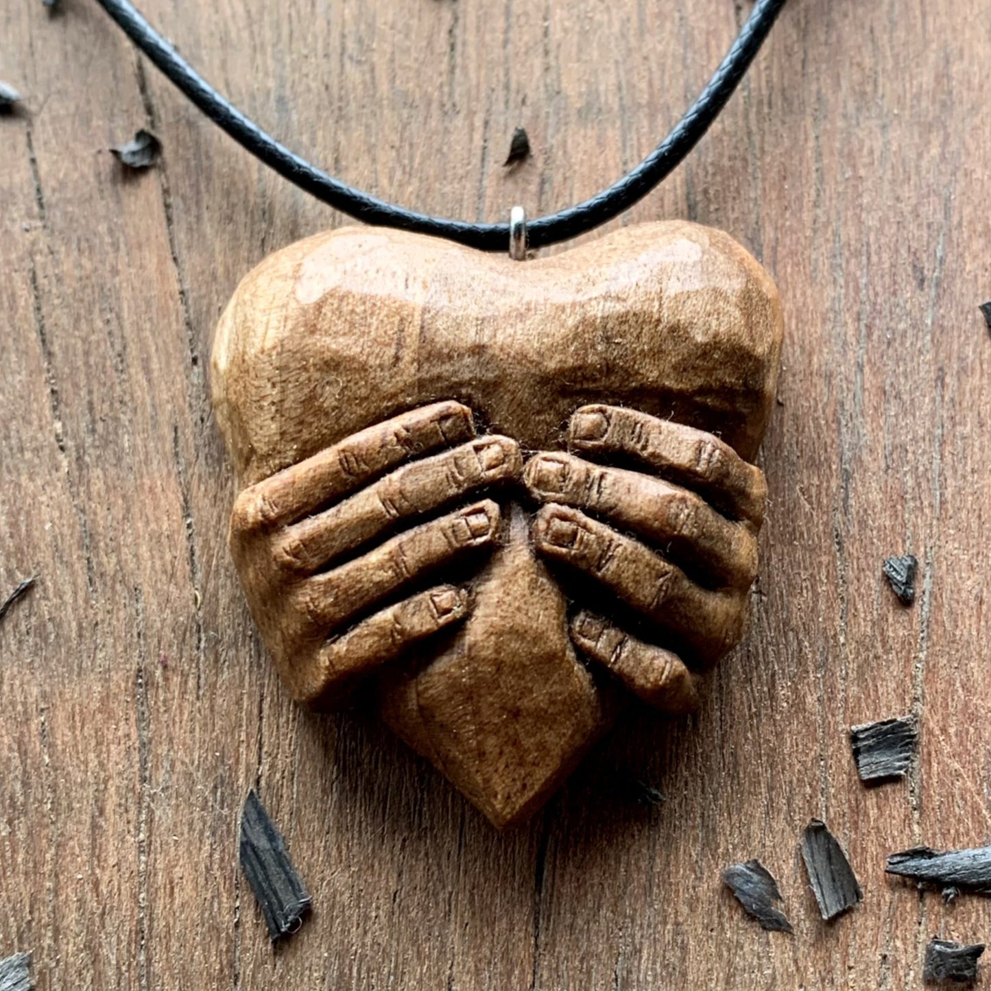 Hands squeezing a Heart Pendant